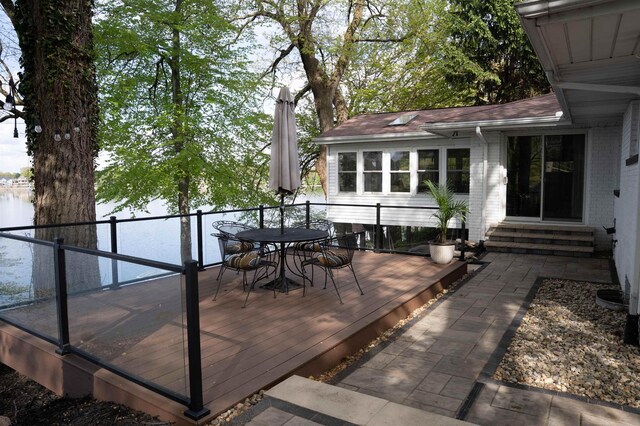 wooden terrace featuring entry steps, outdoor dining space, and a water view