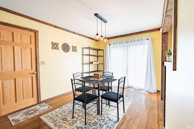 dining space featuring light wood-type flooring, crown molding, and baseboards