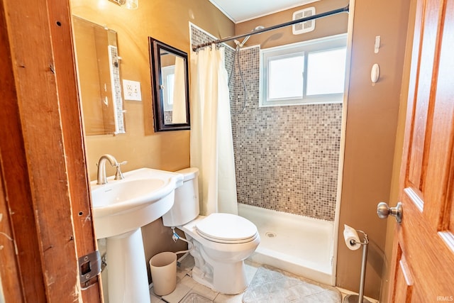 bathroom featuring a stall shower, tile patterned flooring, toilet, and a sink