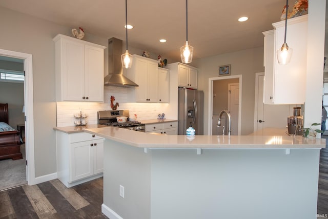 kitchen with stainless steel appliances, wall chimney exhaust hood, dark wood finished floors, white cabinetry, and recessed lighting