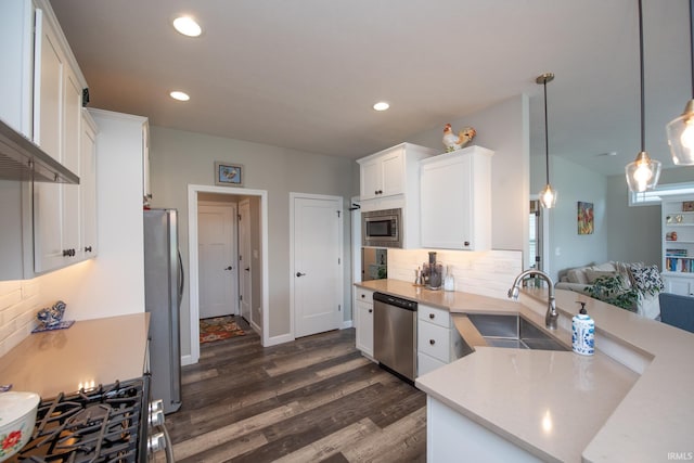 kitchen featuring stainless steel appliances, a sink, dark wood-style flooring, light countertops, and backsplash