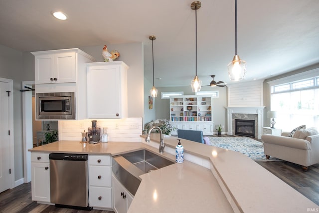 kitchen with stainless steel appliances, a high end fireplace, a sink, light countertops, and white cabinets