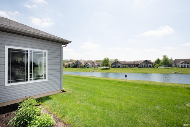 view of green lawn featuring a water view and a residential view