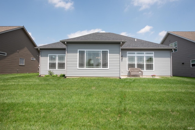 back of house featuring a lawn, a patio area, and a shingled roof