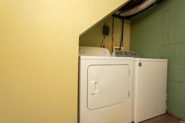 laundry room with separate washer and dryer, concrete block wall, and wood finished floors
