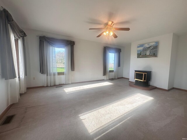9081 N 725 E, Otterbein, IN 47970 - unfurnished living room featuring a wood stove, carpet floors, a ceiling fan, and healthy amount of natural light