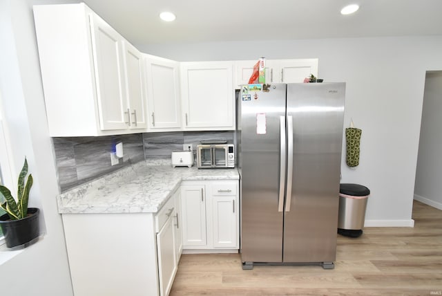 kitchen featuring freestanding refrigerator, white cabinetry, light wood-type flooring, backsplash, and recessed lighting