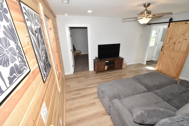 living room featuring a barn door, light wood-style floors, baseboards, ceiling fan, and recessed lighting