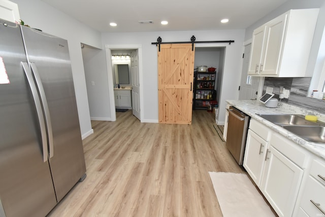 kitchen featuring appliances with stainless steel finishes, a barn door, white cabinetry, light countertops, and light wood-type flooring