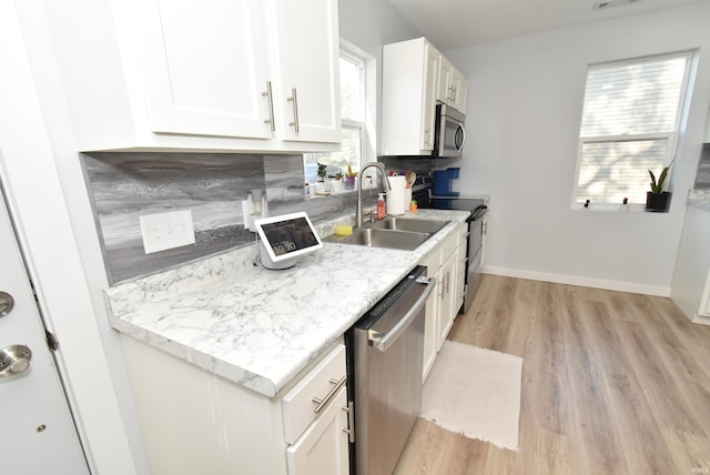 kitchen with stainless steel appliances, a sink, light wood-type flooring, white cabinets, and light countertops