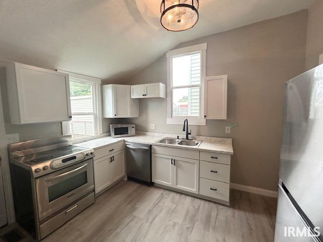 1023 W Franklin St, Evansville, IN 47710 - kitchen featuring a sink, stainless steel appliances, light countertops, light wood finished floors, and lofted ceiling