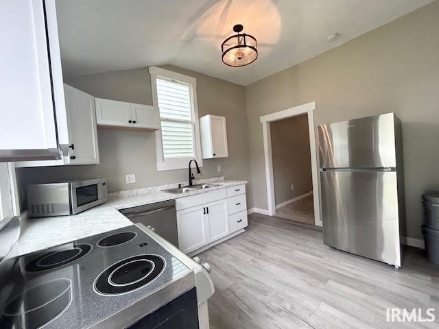 1023 W Franklin St, Evansville, IN 47710 - kitchen featuring appliances with stainless steel finishes, a sink, white cabinetry, light wood-style flooring, and lofted ceiling