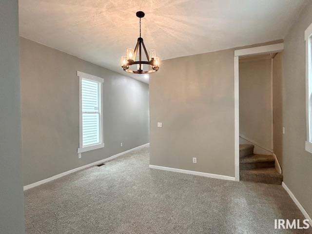 1023 W Franklin St, Evansville, IN 47710 - carpeted spare room with a chandelier, baseboards, and stairway
