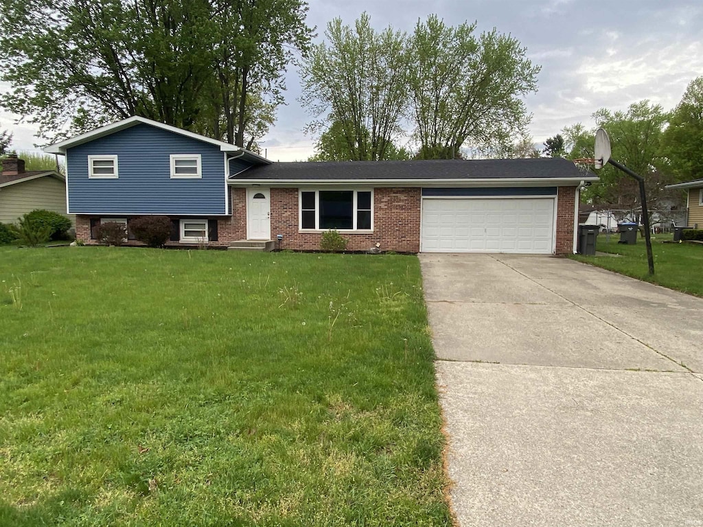 split level home featuring an attached garage, a front lawn, driveway, and brick siding