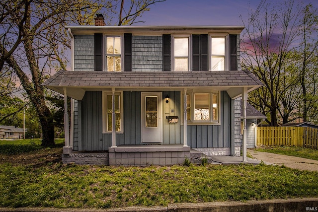 view of front of home featuring a porch, a chimney, board and batten siding, and fence