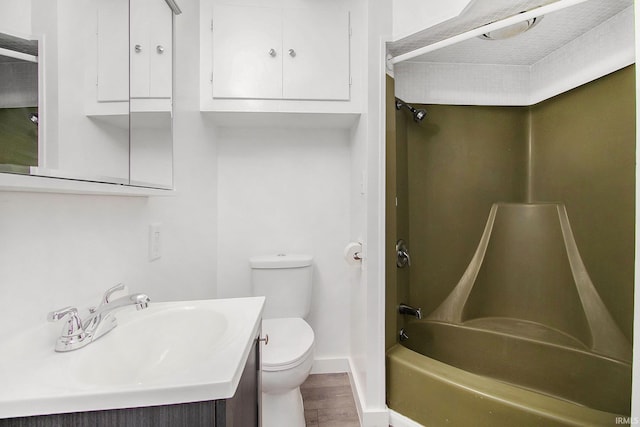 bathroom featuring tub / shower combination, toilet, vanity, wood finished floors, and baseboards