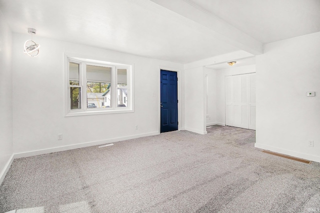 spare room with carpet, baseboards, and beam ceiling