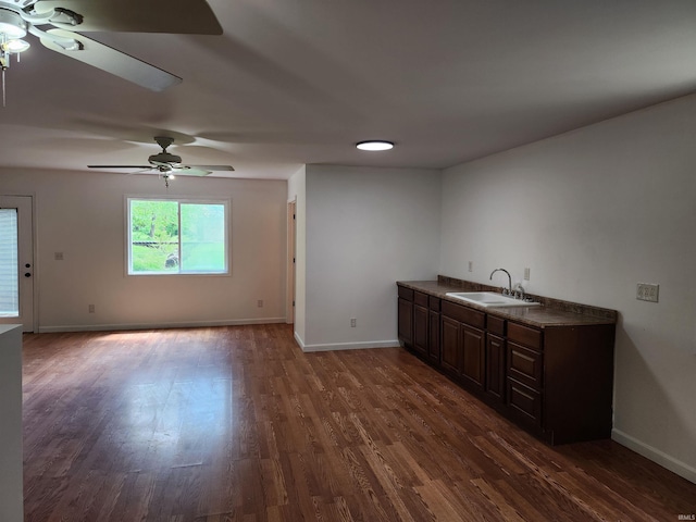 kitchen featuring a sink, ceiling fan, dark wood-type flooring, and baseboards