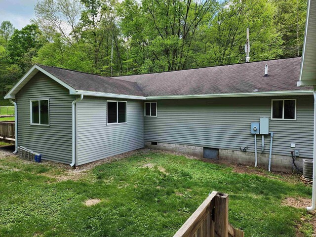 back of house featuring a lawn, a shingled roof, and central AC