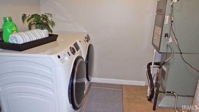 clothes washing area with washer and dryer, baseboards, and light tile patterned floors