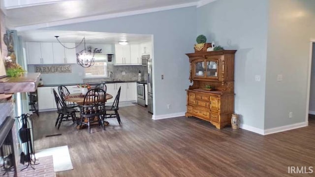 dining space with dark wood-type flooring, a chandelier, and baseboards