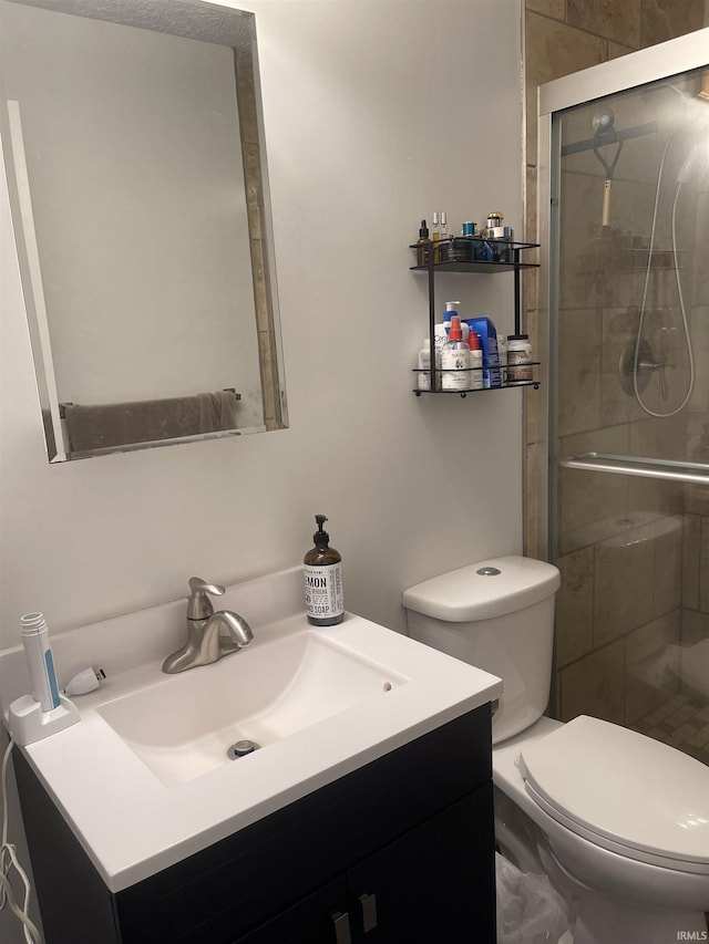 full bathroom featuring a shower stall, toilet, and vanity