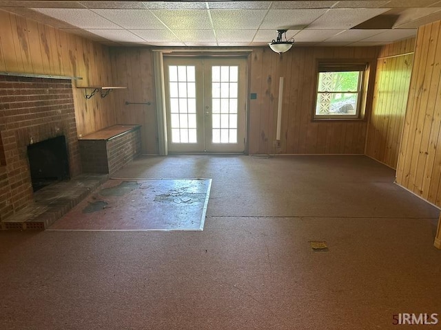 108 S Main St, Patoka, IN 47666 - unfurnished living room featuring french doors, wooden walls, a brick fireplace, and baseboards
