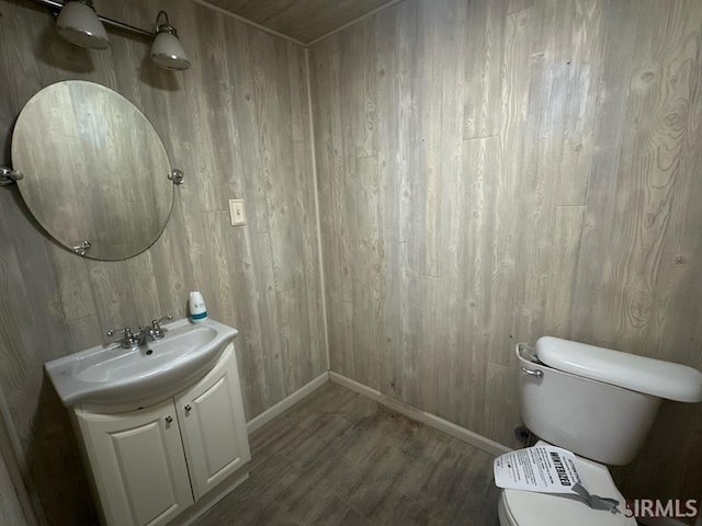 108 S Main St, Patoka, IN 47666 - half bath with baseboards, toilet, wood finished floors, wooden walls, and vanity