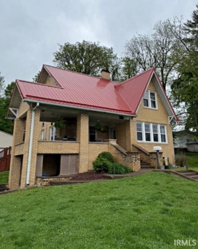 110 W Elnora St, Odon, IN 47562 - back of property with brick siding, a chimney, metal roof, a lawn, and a standing seam roof