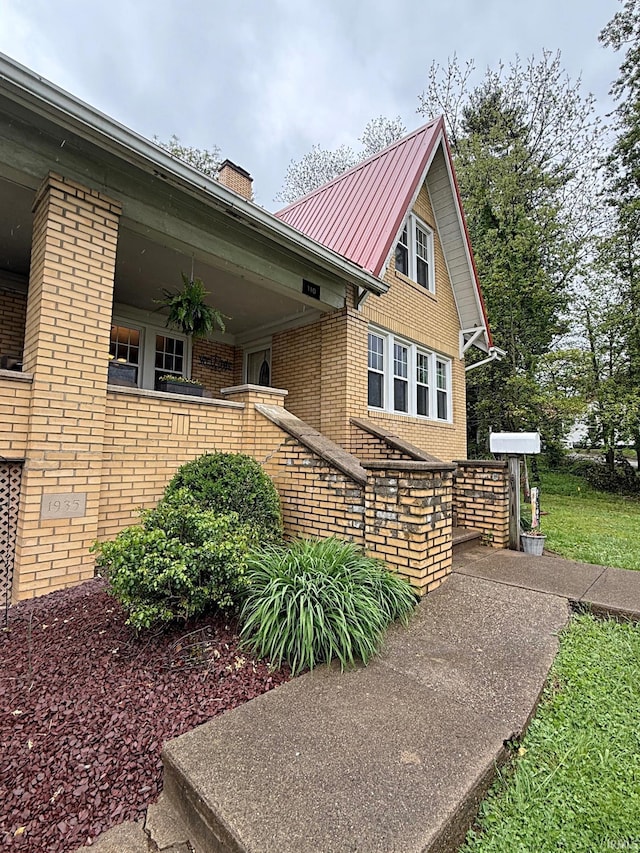 110 W Elnora St, Odon, IN 47562 - view of property exterior with brick siding, a chimney, metal roof, and a standing seam roof