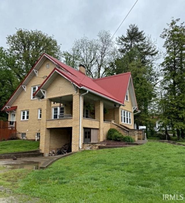 110 W Elnora St, Odon, IN 47562 - view of home's exterior featuring brick siding, a yard, a chimney, and a balcony