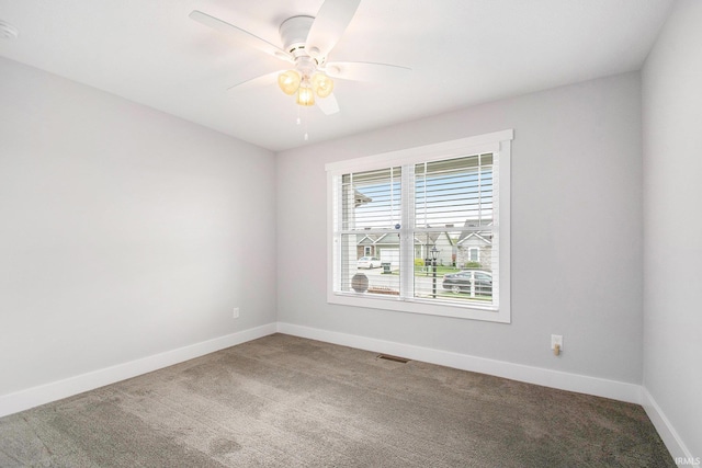 carpeted spare room featuring baseboards, ceiling fan, and a smoke detector