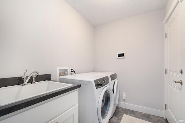 laundry room with baseboards, independent washer and dryer, a textured ceiling, and cabinet space