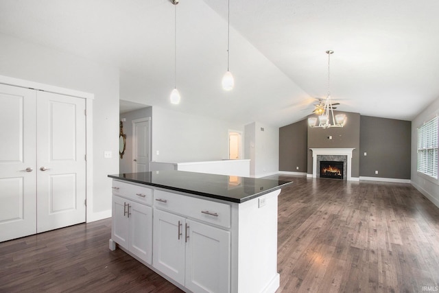 kitchen with dark countertops, vaulted ceiling, dark wood-style floors, a center island, and white cabinetry