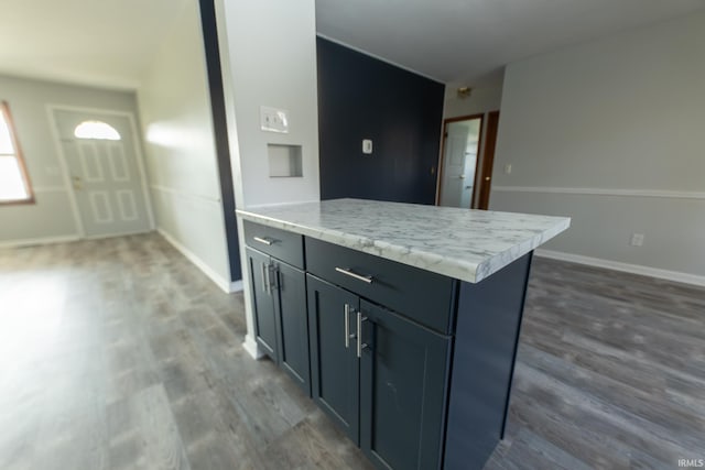 kitchen featuring dark wood-style floors, light countertops, a center island, and baseboards