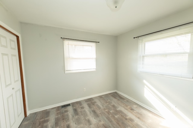 unfurnished bedroom with multiple windows, wood finished floors, and baseboards