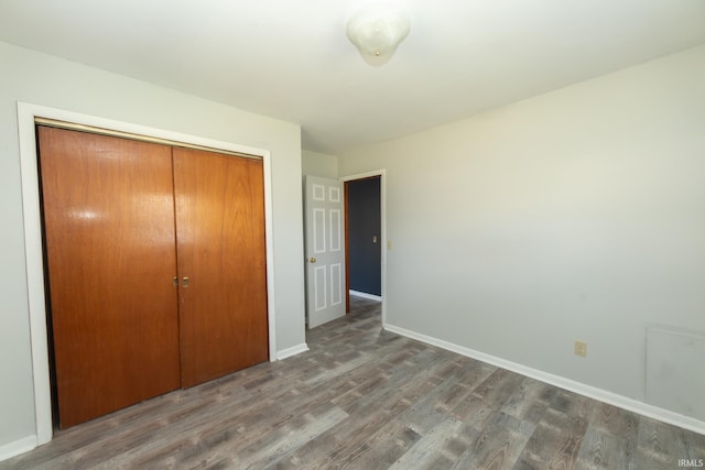 unfurnished bedroom with a closet, wood finished floors, and baseboards