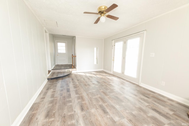 unfurnished living room featuring ceiling fan, wood finished floors, and baseboards
