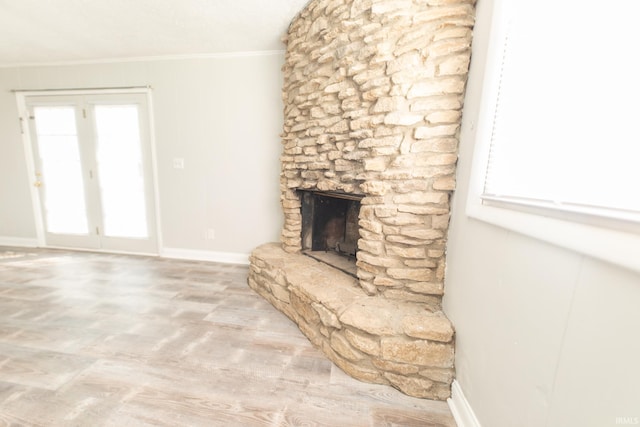 unfurnished living room with crown molding, healthy amount of natural light, baseboards, a fireplace, and wood finished floors