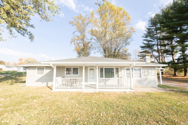 ranch-style home with a chimney, a porch, and a front lawn