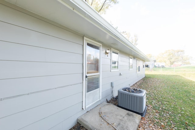 view of home's exterior with central air condition unit and a lawn
