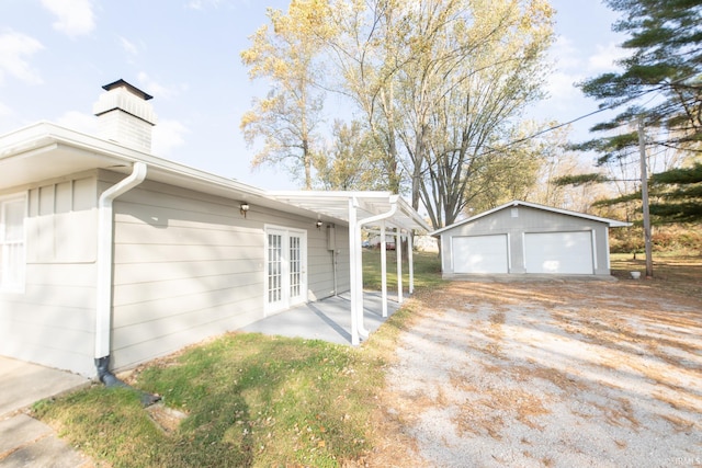 view of side of home with french doors, a garage, an outbuilding, and a chimney