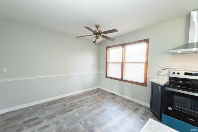 kitchen with range with electric stovetop, wall chimney range hood, wood finished floors, a ceiling fan, and baseboards