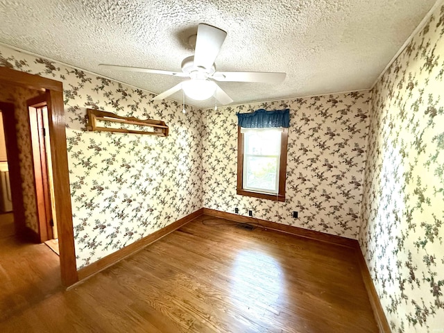 219 W Boone St, Gentryville, IN 47537 - empty room with wood finished floors, a ceiling fan, a textured ceiling, baseboards, and wallpapered walls