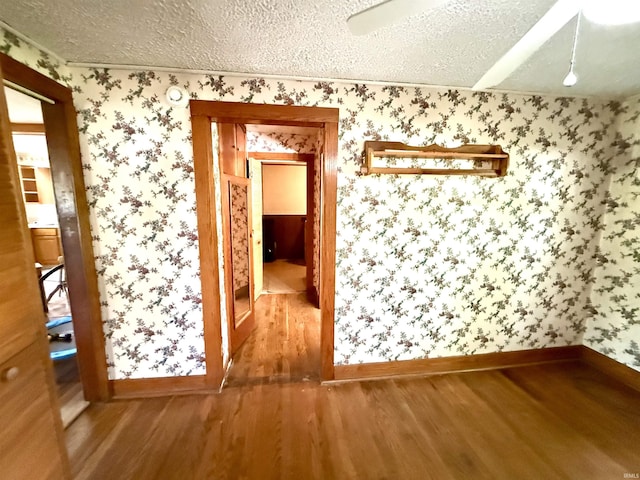 219 W Boone St, Gentryville, IN 47537 - spare room featuring wallpapered walls, wood finished floors, baseboards, and a textured ceiling