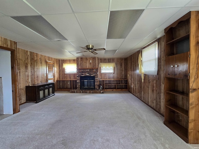 4980 W 200 N, Kokomo, IN 46901 - unfurnished living room with wood walls, a brick fireplace, ceiling fan, carpet flooring, and a paneled ceiling