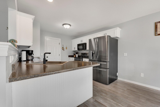 13726 Hamilton Meadows Ln, Fort Wayne, IN 46814 - kitchen with stainless steel appliances, dark countertops, a peninsula, a sink, and white cabinetry