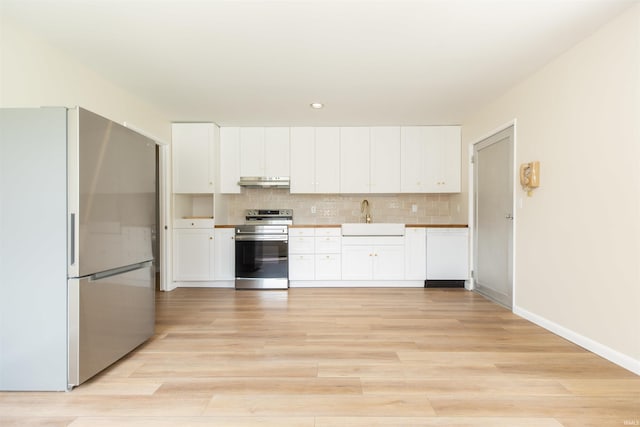 kitchen with appliances with stainless steel finishes, under cabinet range hood, a sink, white cabinets, and recessed lighting