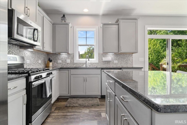 kitchen featuring stainless steel appliances, a sink, dark wood-style floors, tasteful backsplash, and recessed lighting