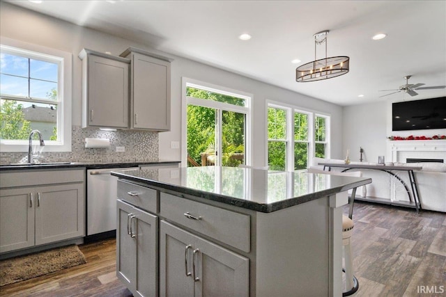 kitchen featuring gray cabinetry, stainless steel dishwasher, a sink, plenty of natural light, and recessed lighting